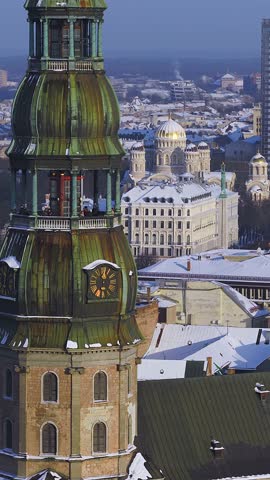 Aerial 4K pan over central Riga, Latvia, past St Peters Church clock tower toward Nativity of Christ Cathedral, Radisson Blu, and Freedom Monument in winter light.