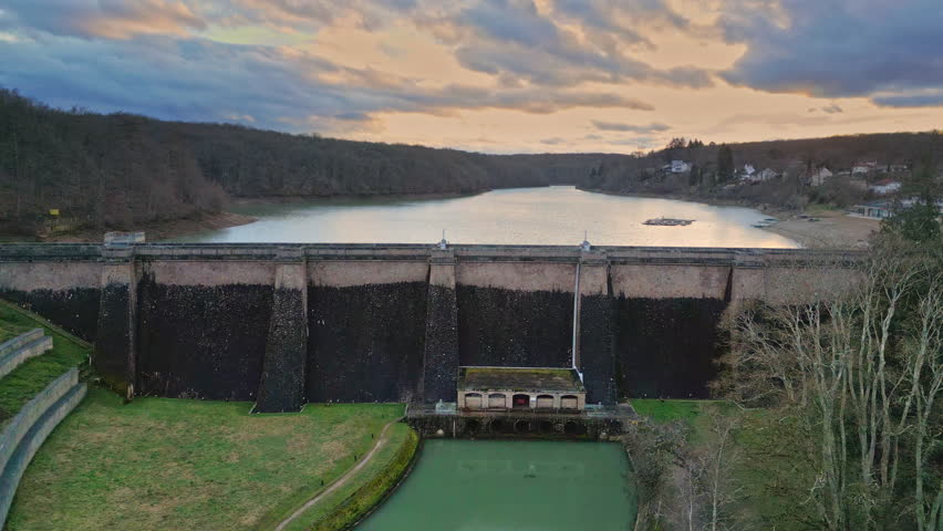 Cinematic drone shots of a dammed river in Burgundy. Features a 25m curved dam, city beach, and nautical sports club. Winter landscape with forest on the opposite shore. Movements: push-in, side tracking, pedestal, and top-down view.