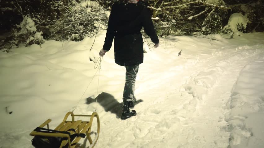 Young woman walking and dragging the sled on the snow