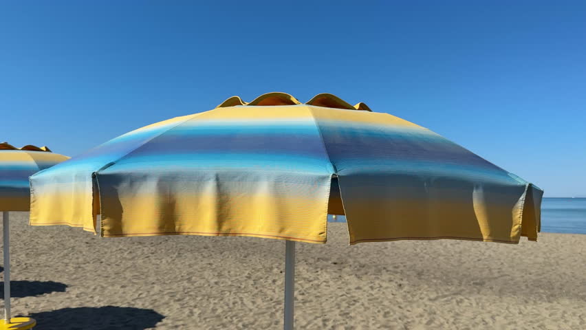 Yellow and blue beach umbrella. Relaxing context. Summer holidays by the sea. General contest and location