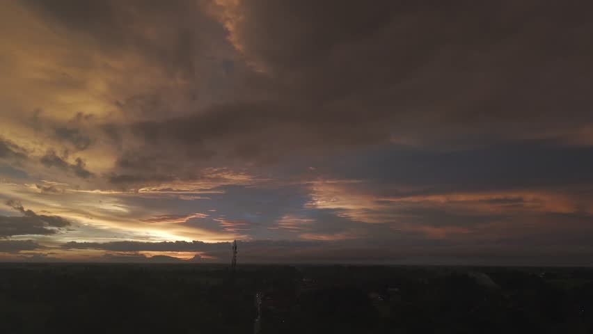 A dark landscape photo with orange and blue hues in the cloudy sky