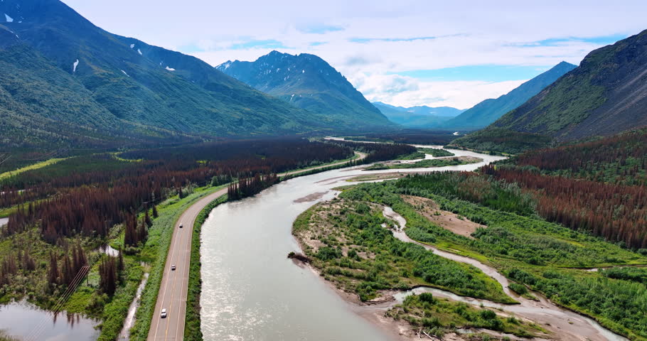 Flight over the river flowing in the picturesque valley among the mountains. Fantastic nature landscapes of Alaska.