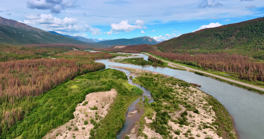 Moving fast over the delta of the branching river. Beautiful mountains surround the area. Alaska landscapes.