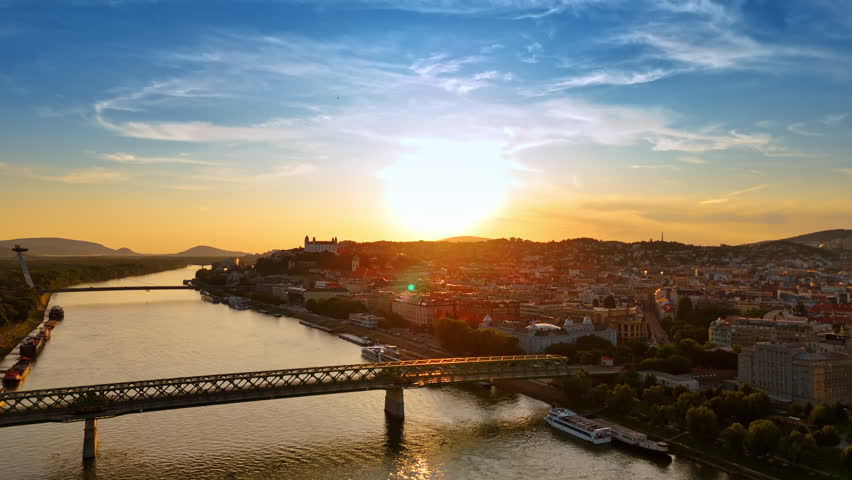Approaching the Old Bridge leading to the old town of Bratislava, Slovakia. Setting sun dazzles the scenery. Aerial view.