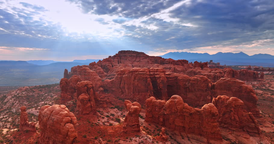 Crooked rounded red canyons in the vast desert. Approaching the striking rocks in the Arches National Park, Utah, USA at sunset.