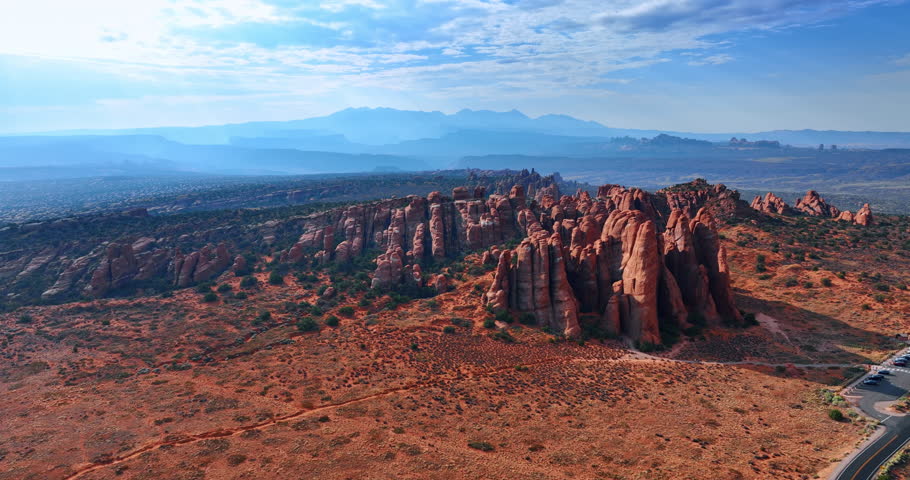 Strangely shaped red rocks with some green bushes growing around. Canyons of the Arches National Park, Utah, USA. Aerial view.