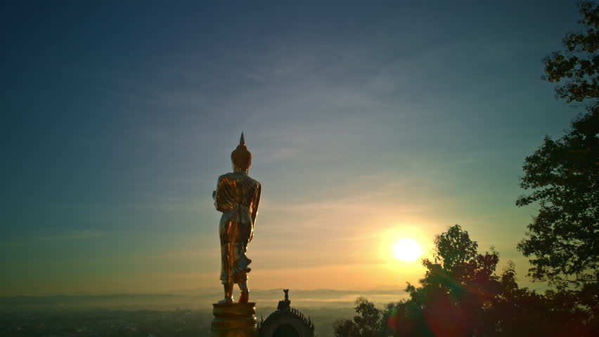 Panoramic Horizon Sunrise Captured in TimeLapse. Wat Khao Noi in Nan Province offers a spiritual sunrise experience, where a golden Buddha statue overlooks the city beneath warm morning light.