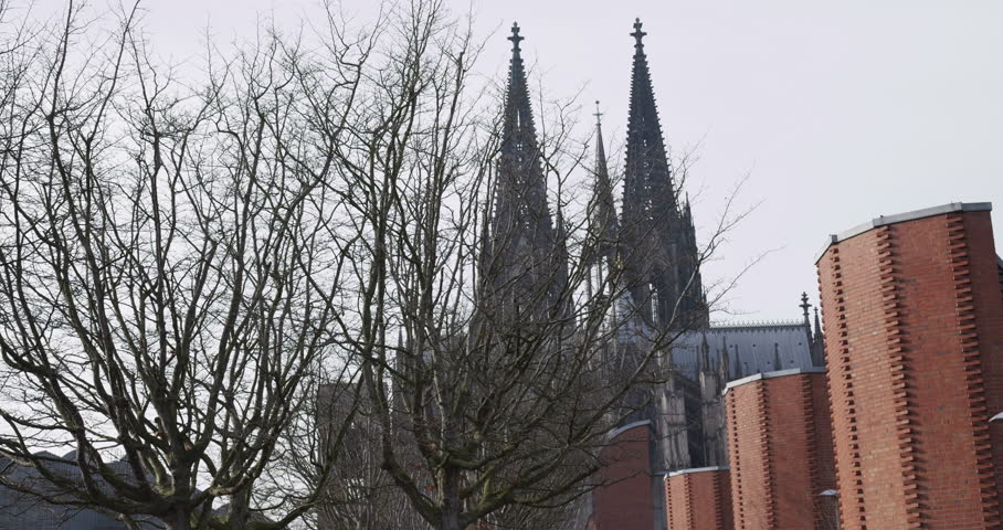 Cologne Cathedral Towers Seen Through Bare Trees and Brick Buildings in Winter Germany