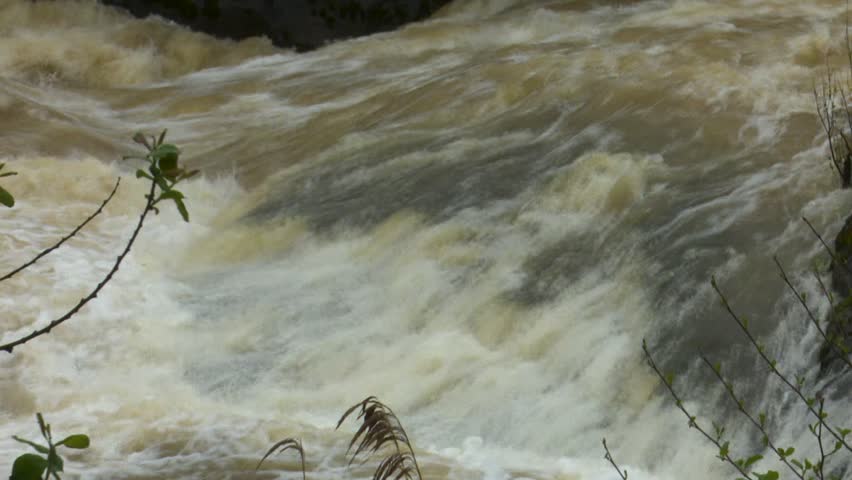 After days of relentless rain, the Cadagua River surges through Alonsotegi with an intensity rarely seen. Its waters, normally calm as they wind between the town’s bridges and wooded banks, now rush forward in a powerful torrent, churning in shades of brown and white. The swollen current crashes against rocks and river walls, carrying branches and debris as a reminder of the storm’s force. In the misty air, the roar of the river dominates the landscape, capturing a raw and dramatic moment in this Basque valley as nature briefly reclaims its strength