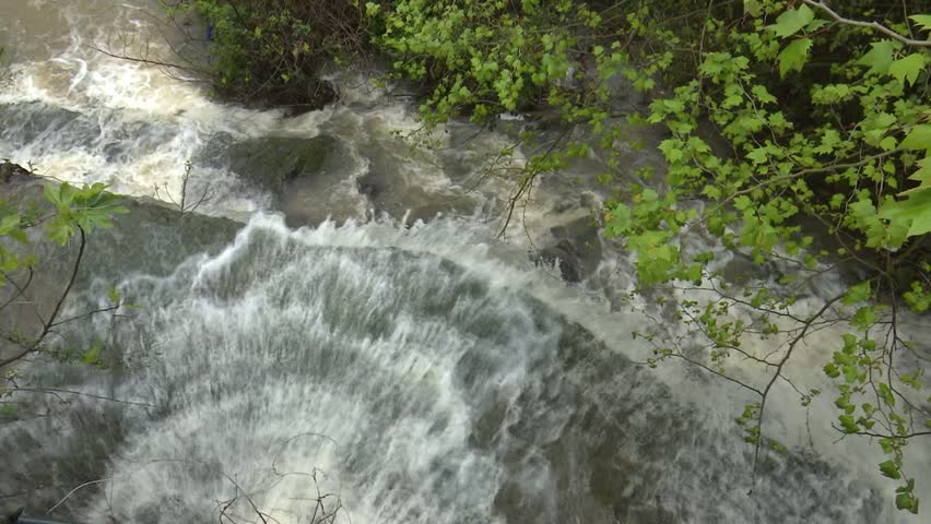 After days of relentless rain, the Cadagua River surges through Alonsotegi with an intensity rarely seen. Its waters, normally calm as they wind between the town’s bridges and wooded banks, now rush forward in a powerful torrent, churning in shades of brown and white. The swollen current crashes against rocks and river walls, carrying branches and debris as a reminder of the storm’s force. In the misty air, the roar of the river dominates the landscape, capturing a raw and dramatic moment in this Basque valley as nature briefly reclaims its strength