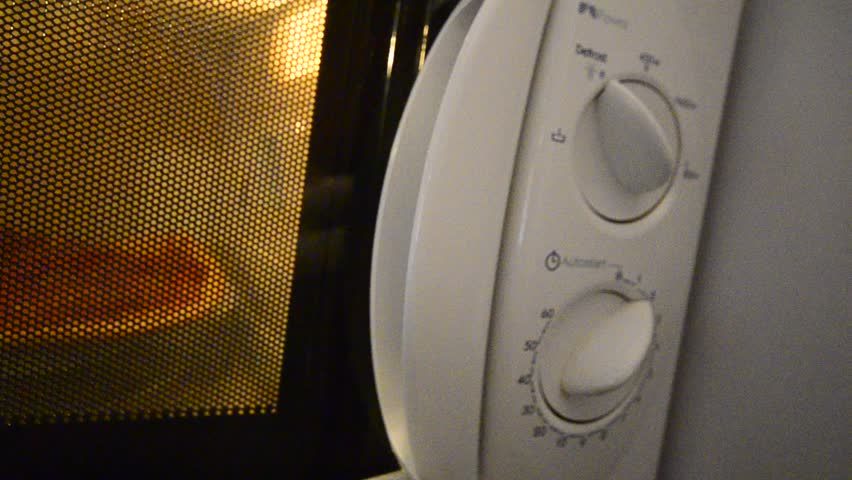 Cooking using a microwave oven. Pizza is preparation Close up macro dolly move