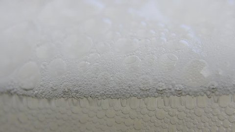 Beer Foam rising and filling the glass - HD, 1080i macro shot of beer foam flowing out of glass. More beer is poured and the foam rises.