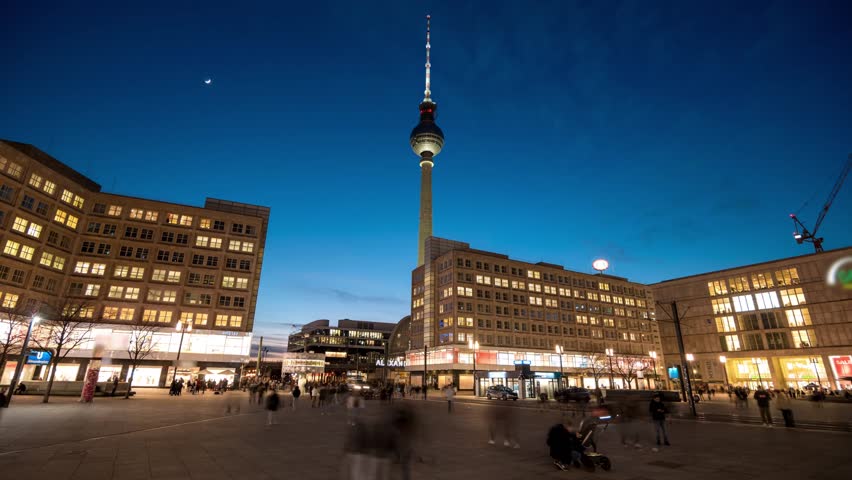 Night Timelapse of Alexanderplatz and TV Tower in Berlin. Illuminated Fernsehturm and City Square at Twilight with Moving People and Glowing City Lights in the German Capital.