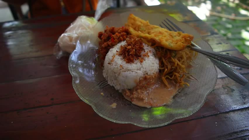 Indonesian Nasi Uduk Coconut Rice with Omelette, Fried Noodles, Tempeh, and Peanut Sauce on Wooden Table
