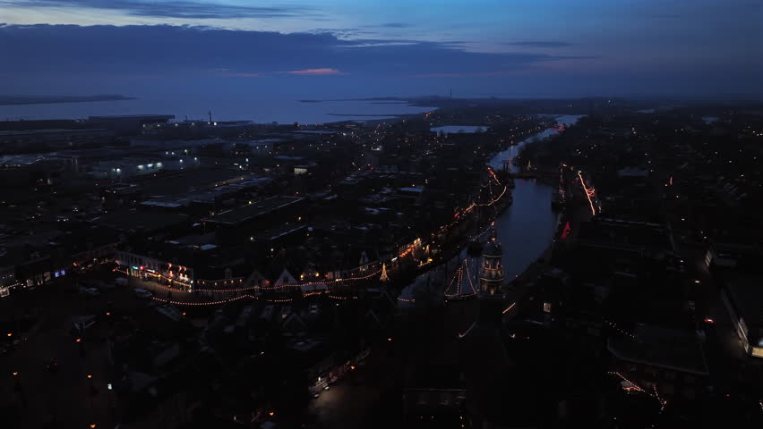 An european historic waterfront at night, featuring an illuminated church and traditional sailing vessels lit in the harbor