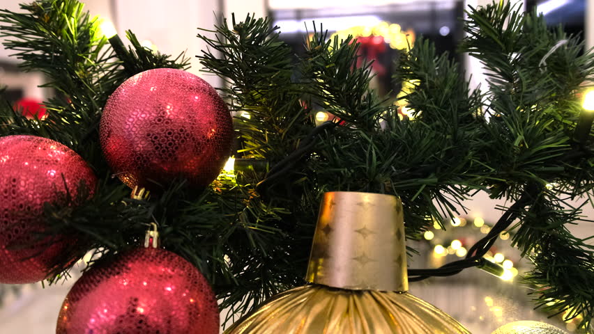 Close-up view of shiny, vibrant ornaments in red and gold hues, reflecting light beautifully and adding festive cheer to the Christmas tree décor.