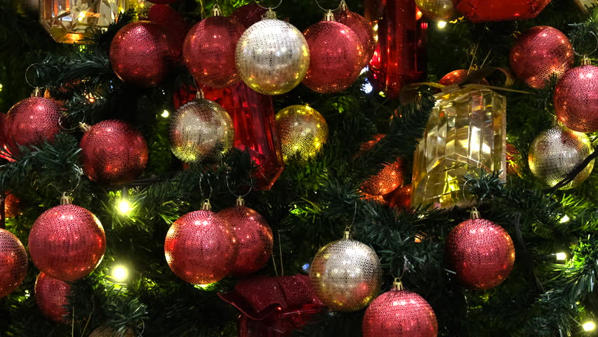 Close-up view of shiny, vibrant ornaments in red and gold hues, reflecting light beautifully and adding festive cheer to the Christmas tree décor.