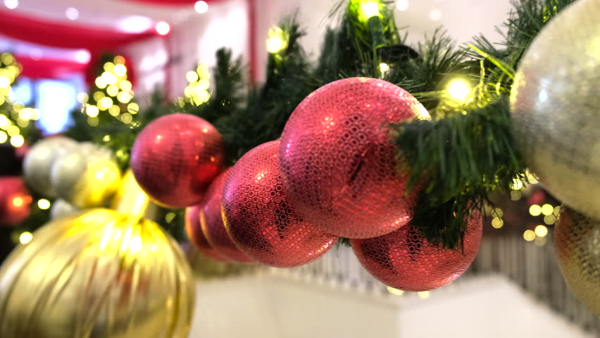 Close-up view of shiny, vibrant ornaments in red and gold hues, reflecting light beautifully and adding festive cheer to the Christmas tree décor.