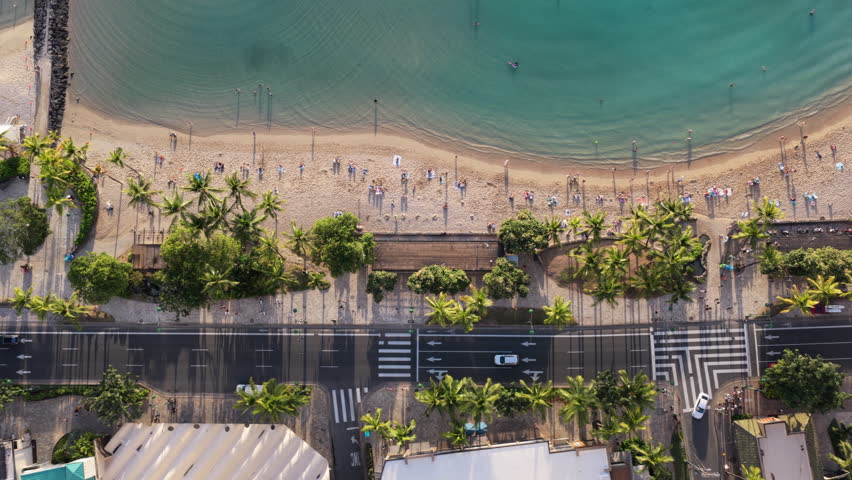 Top down view of main street by the ocean in Waikiki Beach at sunset, Hawaii. Street, cars and people walking on promenade