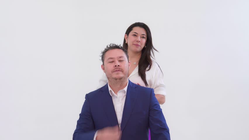 Happy woman hugging and kissing her boyfriend from behind on a white background