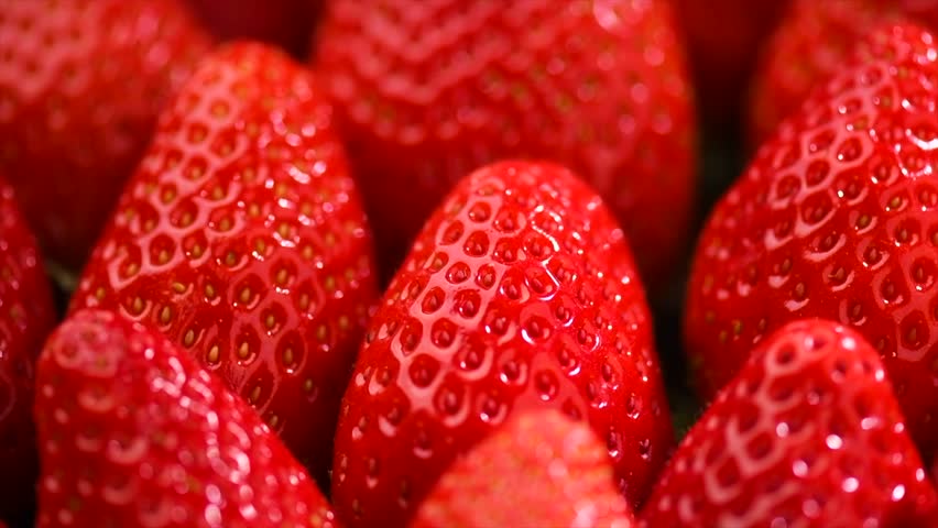 Strawberry, fresh ripe strawberries background close-up. Organic Vegetarian healthy food backdrop, macro shot. Slow motion. From above. 