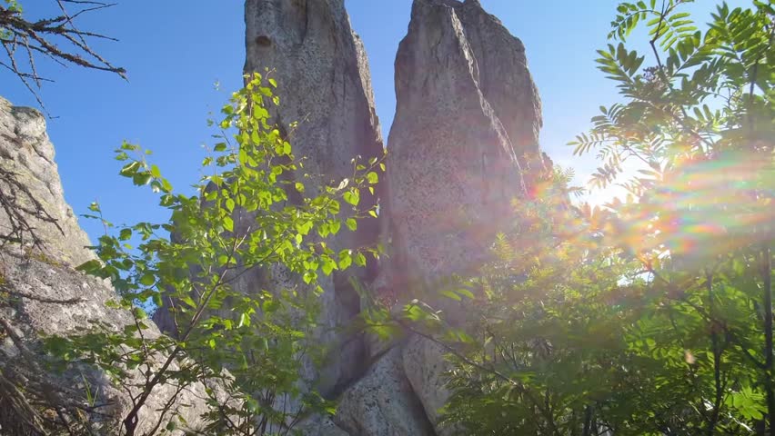 A low-angle, sunlit shot capturing the towering, rugged rock formations (specifically the "Two-headed Hill" or Dvuglavaya Sopka) in Taganai National Park, near Zlatoust, Chelyabinsk Oblast, Southern U