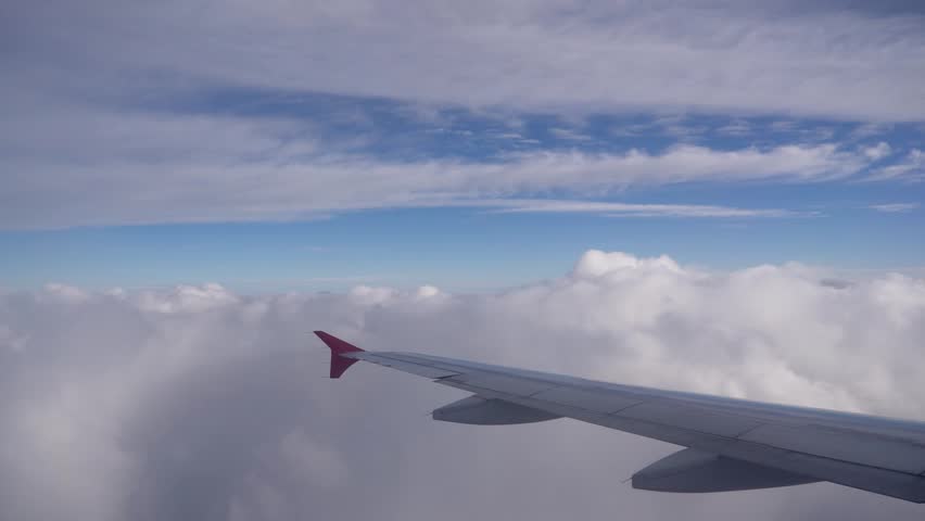 An airplane wing and a timelapse view of it flying over clouds