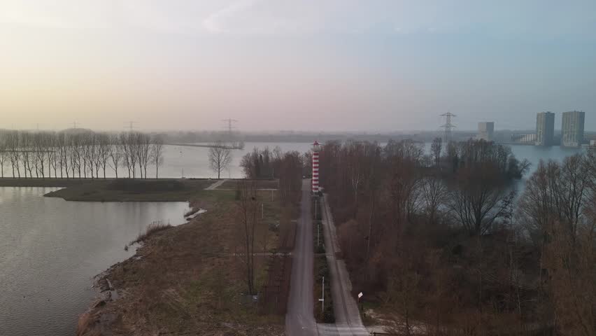 Drone Approaching Island Lighthouse Over Path With Lake and City View