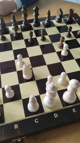 A young child learns how to play chess and captures a white piece with a black pawn. A heartwarming moment of learning and victory in a domestic setting.