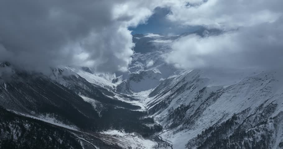 Aerial footage of beautiful high altitude snowcapped mountains and forest landscape