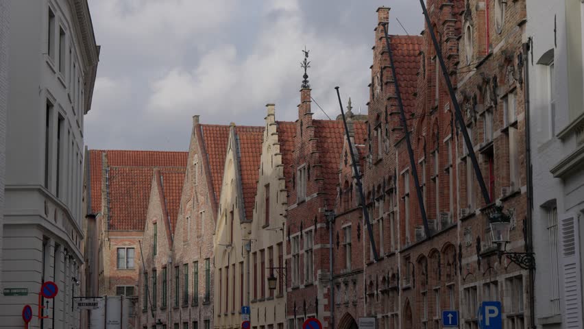Traditional brick gabled houses line a narrow historic street in Bruges, Belgium