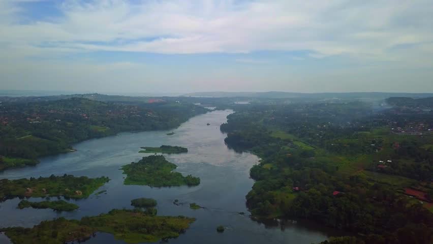 Nile river begins its journey, winding through the verdant Jinja region of Uganda, surrounded by rolling hills covered in greenery and dotted with serene islands, creating a ecosystem on its source