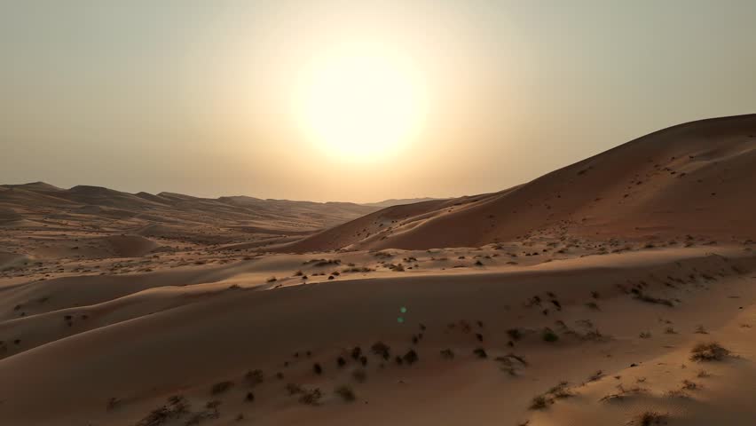 Fly over sand dunes during a sunset in the Empty Quarter in the United Arab Emirates during a warm day.