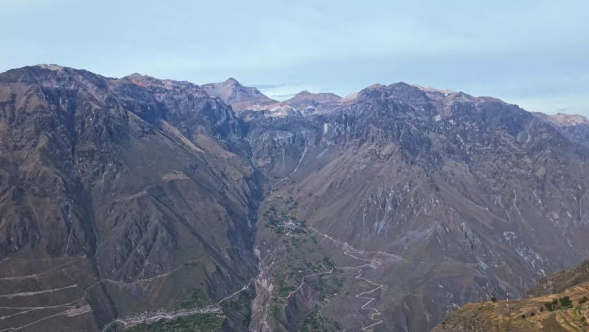 A far-back drone pullback reveals the full rim of Colca Canyon, showcasing the immense scale and open space created by the canyon’s vast walls and landscape.
