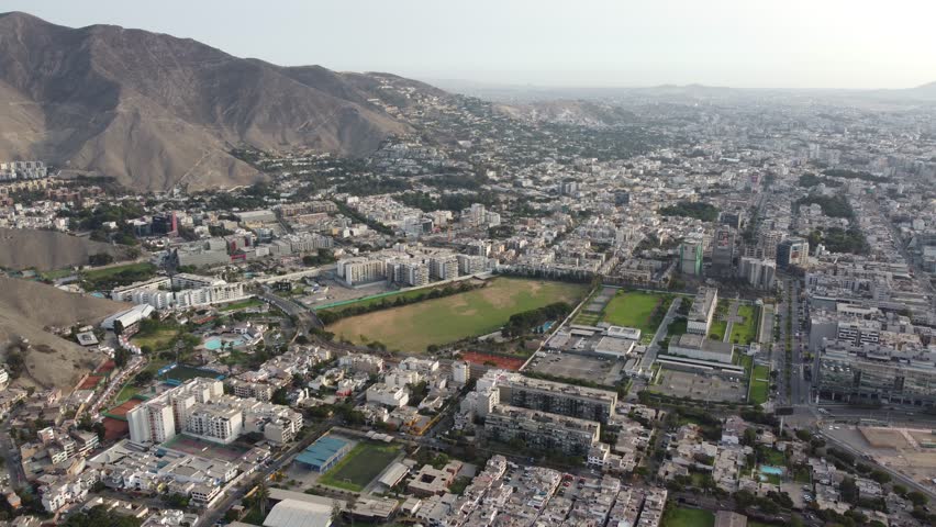 Aerial view of Lima with mountains and neighborhoods, Sunlit Lima cityscape featuring racetrack and expansive suburbs