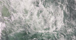 Top down drone aerial of Nazare Portugal Atlantic shorebreak, churning sea foam patterns and wave turbulence, cinematic abstract ocean texture background for motion and energy - Powered by Shutterstock - Get 15% off with code: PIKWIZARD15