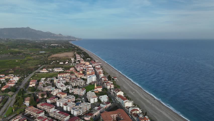 Coastal town with beach, mountains, blue sky, peaceful seaside atmosphere