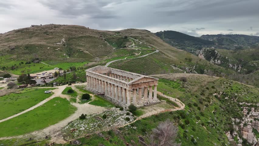 Ancient ruins on a hill under cloudy skies with green landscape views