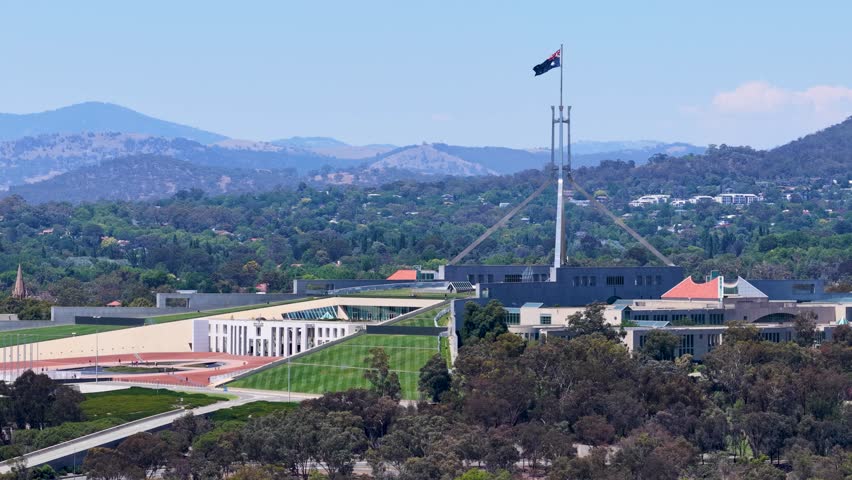 Static wide shot of the Australian Parliament House under a clear blue sky in Canberra