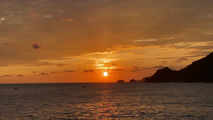 Peaceful tropical sunset over the ocean with gentle waves and warm golden sky, ideal for background, travel, and nature content.