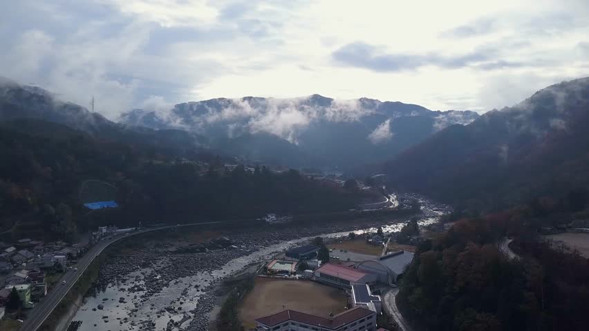 Highway follows curve in Kiso River in cloudy Nagiso Japan mtn valley