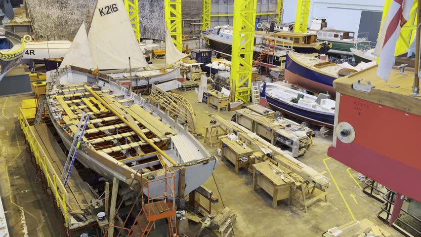 Wooden sailboats under restoration inside Portsmouth naval workshop
