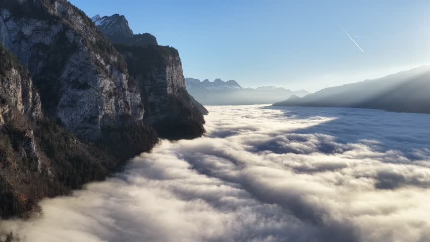 aerial view of alpine cliffs rising above thick cloud layer