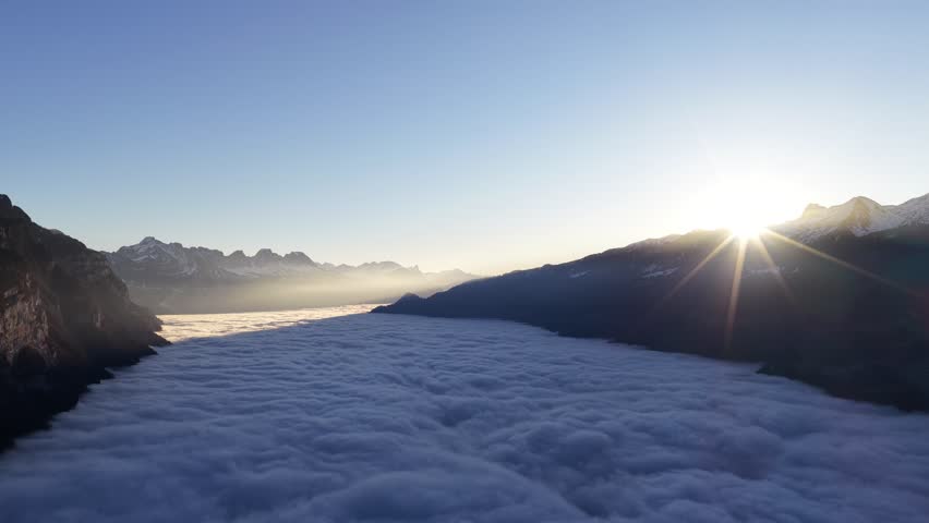 aerial view of sunrise above alpine cloud layer in switzerland