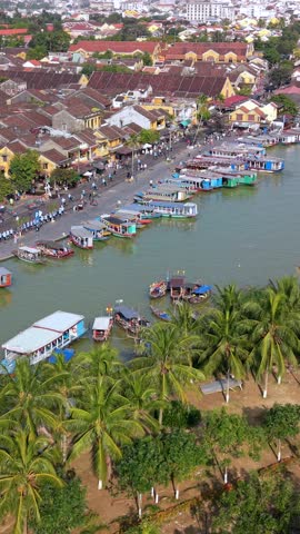 Aerial view of Hoi An old town along the river, featuring traditional architecture, colorful rooftops, boats, and vibrant riverside life in one of Vietnam