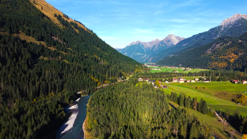 Golden autumn light over Lechtal valley with blue Lech river, forests and Alpine mountains, aerial view