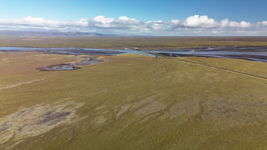 Road in Iceland. Cars are driving along the road. In the background mountains, a glacier, sky, clouds. 4K. Drone