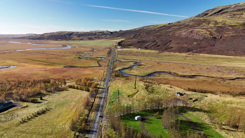 Road in Iceland. Cars are driving along the road. In the background mountains, a glacier, sky, clouds. 4K. Drone