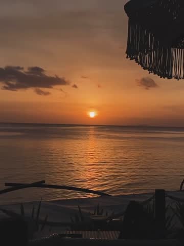 Golden sunset silhouette over calm ocean horizon with structure outline