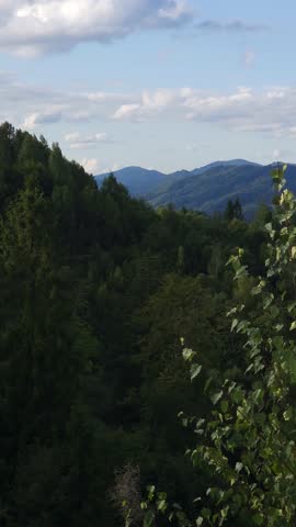 Sunny panoramic landscape with forested hills and dramatic cloud formations